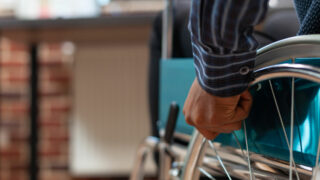 Acercamiento a la mano de una persona con discapacidad en silla de ruedas